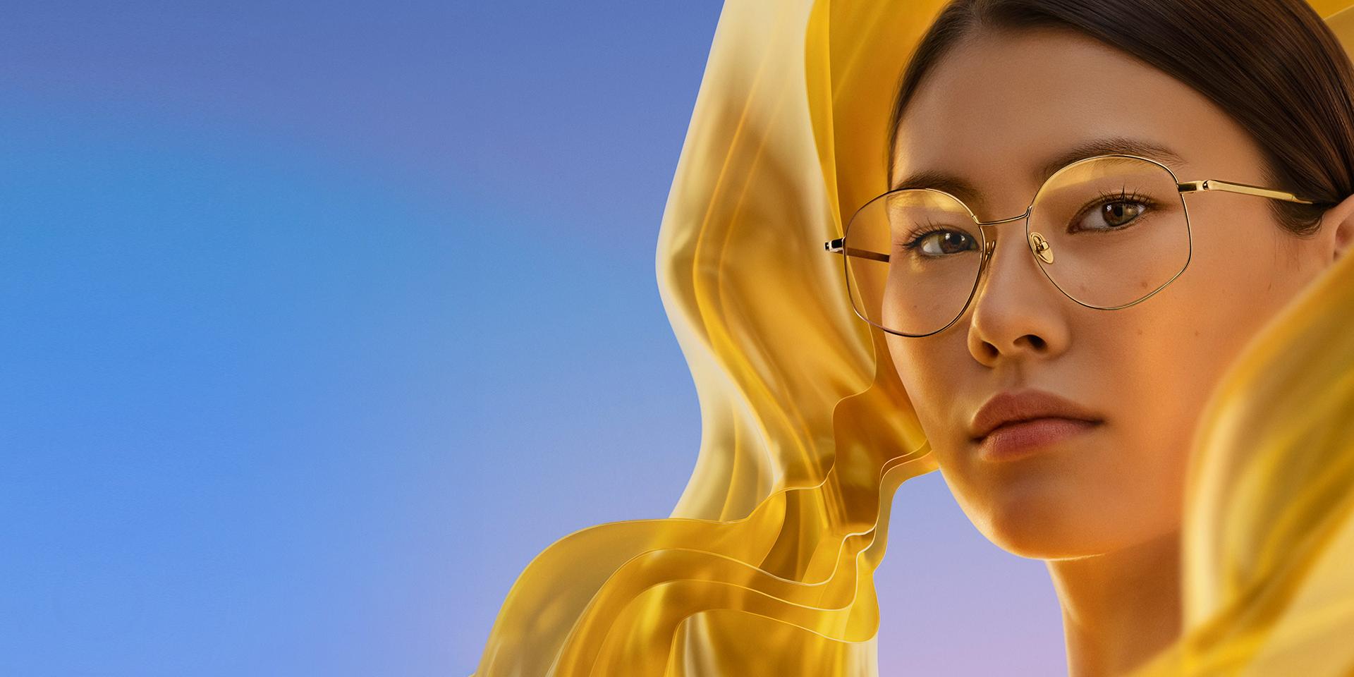 Mujer con lentes transparentes con ZEISS DuraVision Gold UV, que añade un sutil reflejo dorado a los lentes.